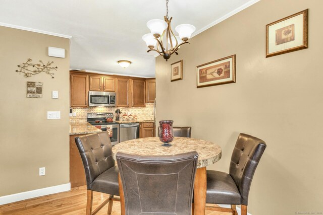 dining area with light hardwood / wood-style flooring, crown molding, and an inviting chandelier