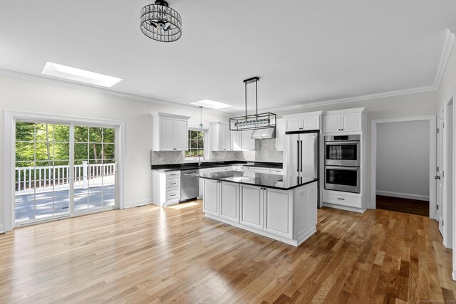 289 Young St, East Hampton, CT 06424 - kitchen featuring dark countertops, backsplash, appliances with stainless steel finishes, a skylight, and white cabinetry