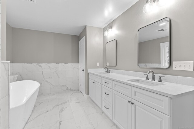 289 Young St, East Hampton, CT 06424 - bathroom with double vanity, a freestanding tub, marble finish floor, and a sink
