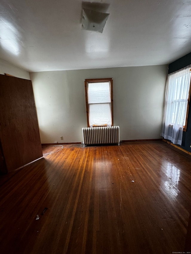 spare room featuring dark hardwood / wood-style floors and radiator