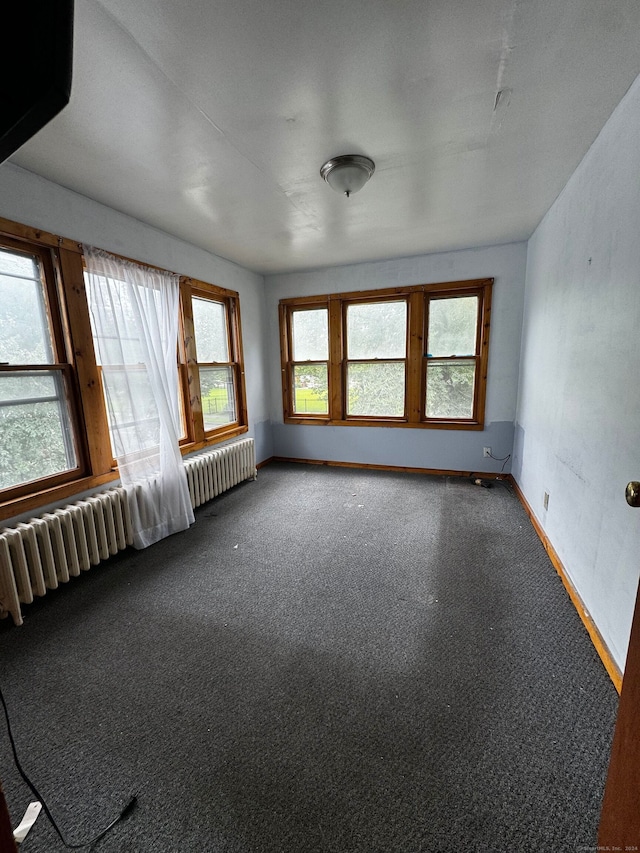 carpeted empty room featuring radiator heating unit