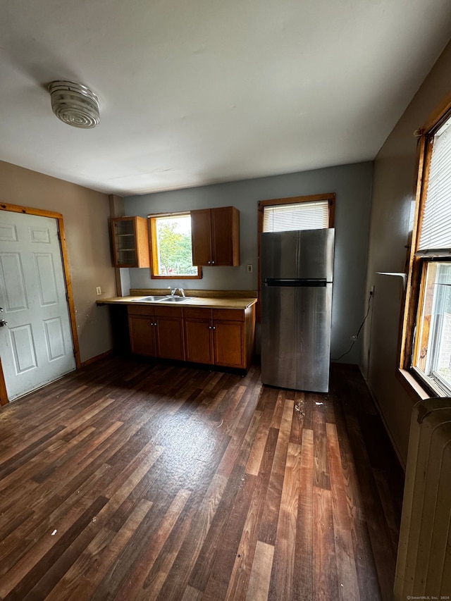 kitchen featuring radiator, sink, dark hardwood / wood-style floors, and stainless steel fridge