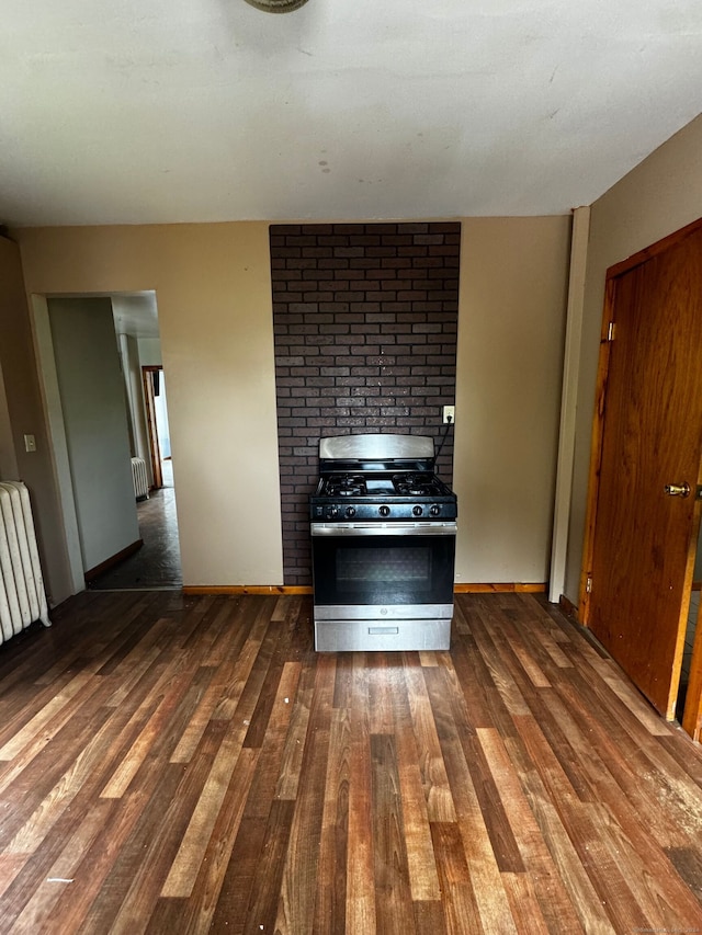 kitchen featuring dark wood-type flooring, radiator, and stainless steel gas range oven