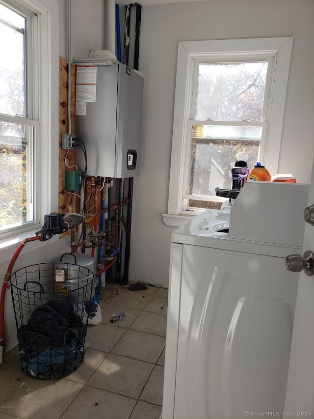 laundry room with water heater, a healthy amount of sunlight, washer / dryer, and light tile patterned floors