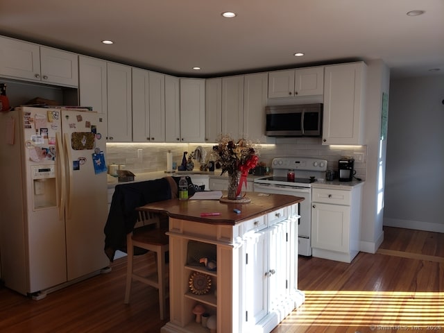 kitchen featuring white appliances, a center island, white cabinetry, and tasteful backsplash