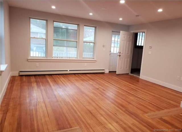 spare room featuring baseboard heating and light wood-type flooring