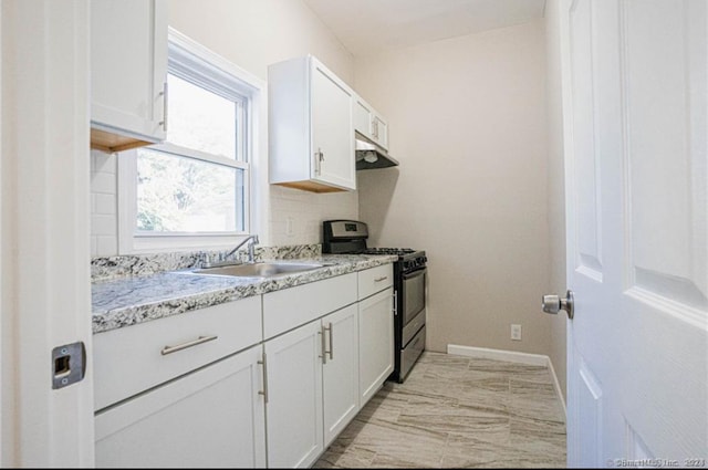 kitchen featuring sink, stainless steel gas range oven, white cabinets, and light stone counters