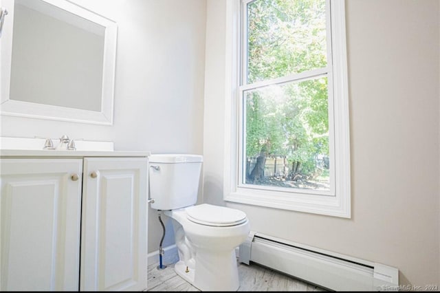 bathroom featuring toilet, a healthy amount of sunlight, vanity, and a baseboard radiator