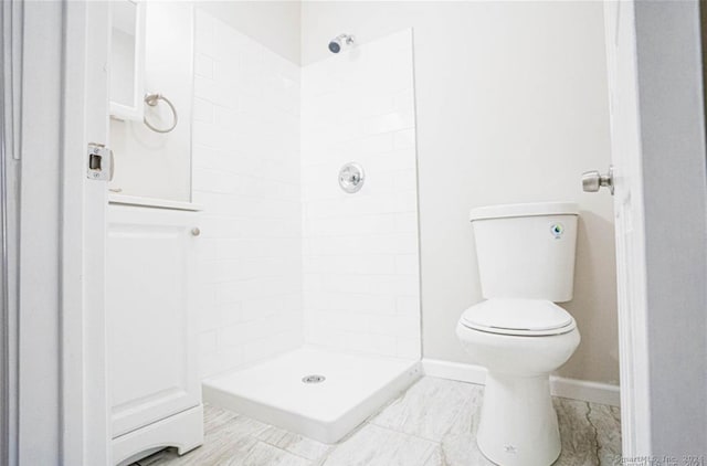 bathroom featuring tiled shower and toilet