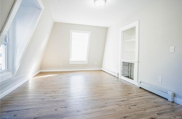 bonus room with a baseboard heating unit and light wood-type flooring