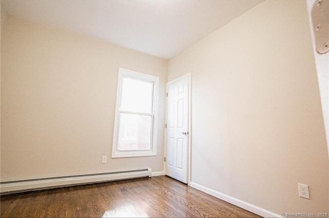 empty room with hardwood / wood-style flooring and a baseboard heating unit