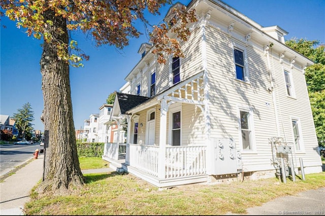 view of property exterior with covered porch and a lawn