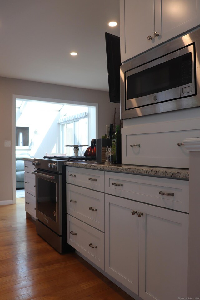 kitchen featuring light hardwood / wood-style flooring, a healthy amount of sunlight, stainless steel microwave, and stove