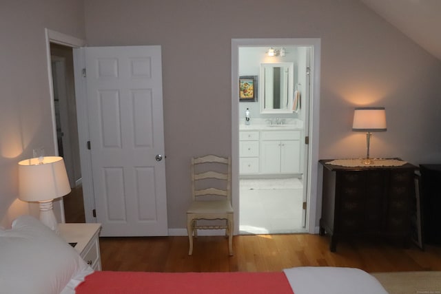 bedroom featuring vaulted ceiling, wood-type flooring, sink, and ensuite bath