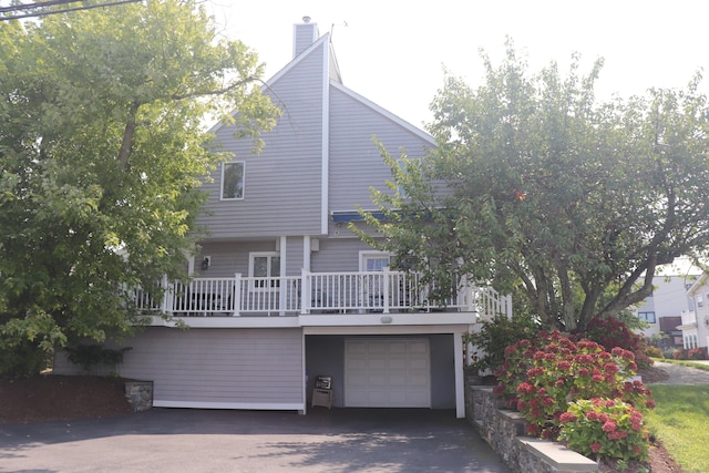 exterior space with driveway, a chimney, and an attached garage