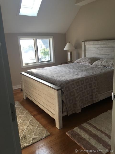 bedroom featuring lofted ceiling with skylight and dark hardwood / wood-style flooring