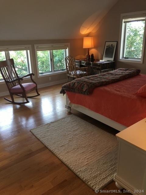 bedroom with lofted ceiling, baseboards, and wood finished floors