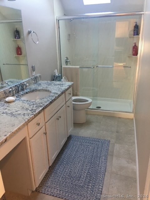 bathroom featuring tile patterned floors, an enclosed shower, vanity, and toilet