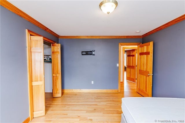 unfurnished bedroom with crown molding and light wood-type flooring