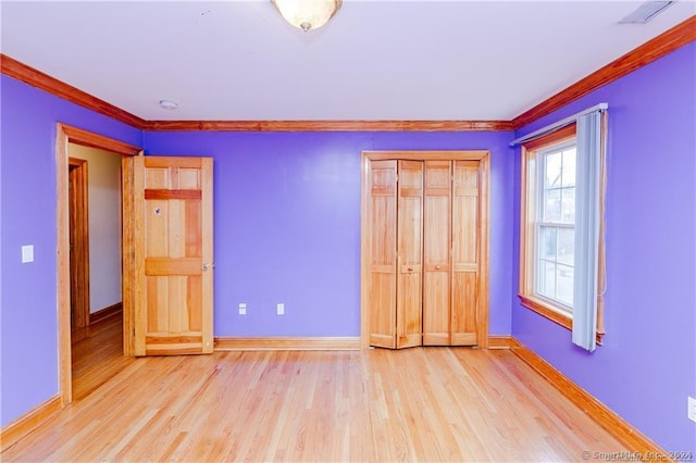 unfurnished bedroom featuring a closet, light hardwood / wood-style floors, and crown molding