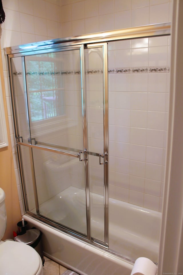 bathroom with combined bath / shower with glass door and toilet