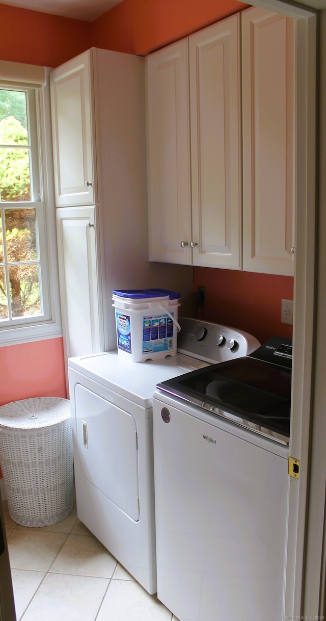 laundry room featuring independent washer and dryer, light tile patterned floors, and cabinets