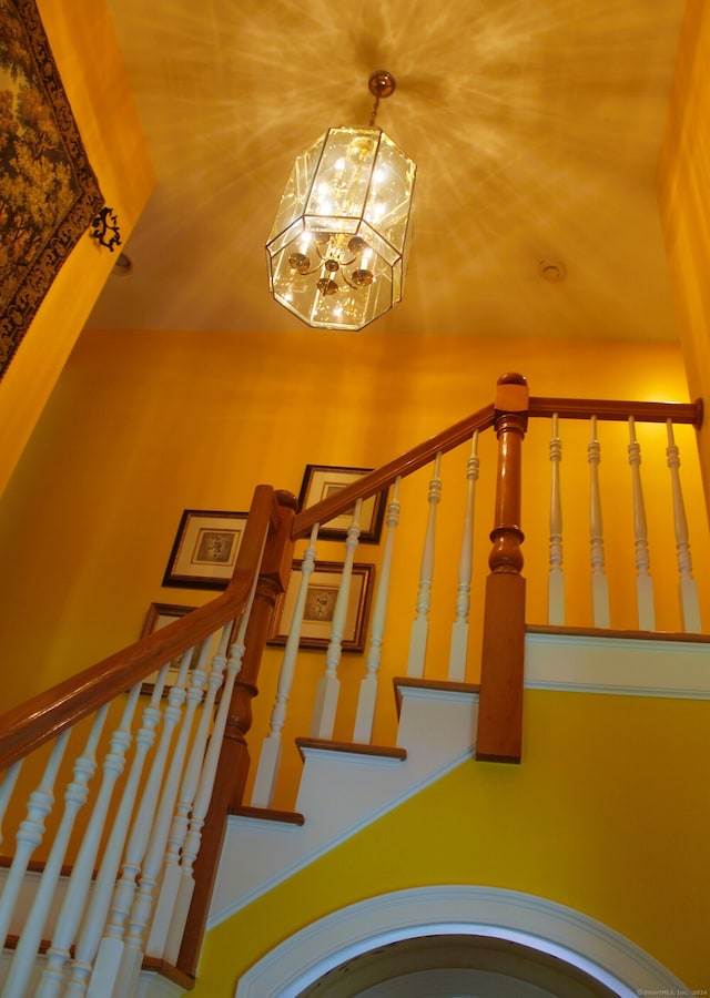 stairway with a towering ceiling and an inviting chandelier