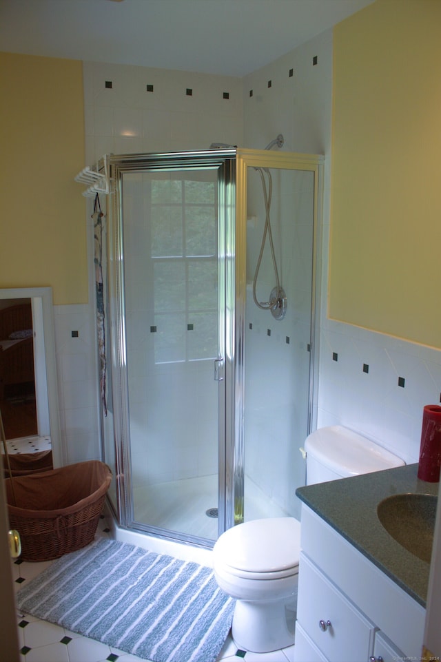 bathroom featuring tile patterned floors, toilet, vanity, and tile walls