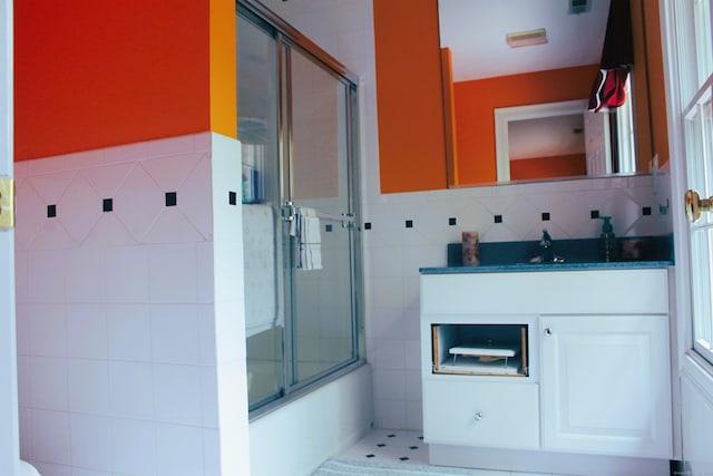 bathroom with tile walls, enclosed tub / shower combo, vanity, and decorative backsplash