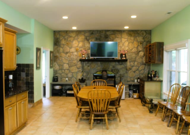 dining space featuring light tile patterned flooring and a stone fireplace