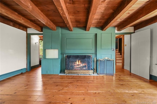 unfurnished living room featuring wood ceiling, light hardwood / wood-style floors, beam ceiling, and a tiled fireplace