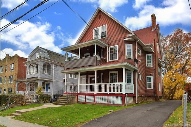 view of front of property with a front lawn, a balcony, and a porch