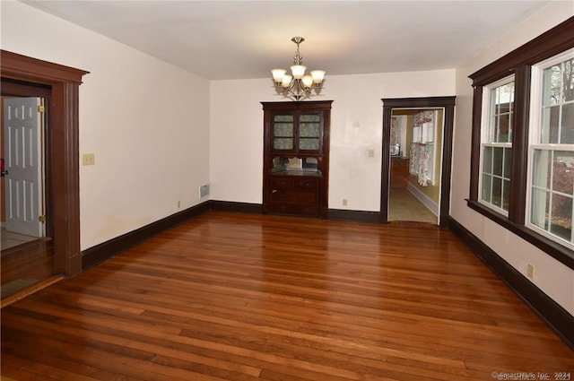 empty room with hardwood / wood-style floors and a notable chandelier