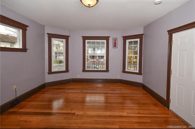 empty room with dark wood-type flooring and a healthy amount of sunlight