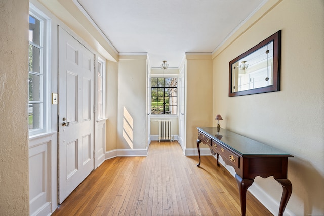 entrance foyer featuring light wood-type flooring, radiator heating unit, and crown molding