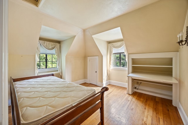 bedroom with multiple windows, light wood-type flooring, and vaulted ceiling