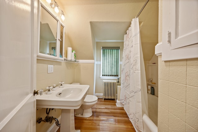 bathroom with shower / tub combo with curtain, radiator, wood-type flooring, tile walls, and toilet