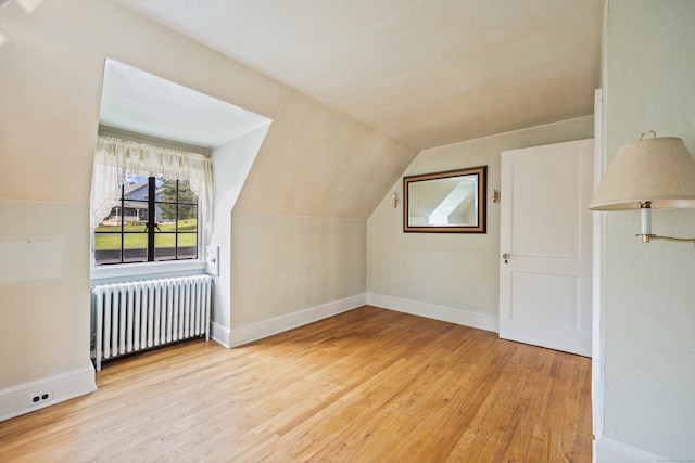 bonus room with light hardwood / wood-style flooring, lofted ceiling, and radiator