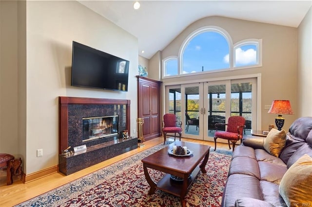 living room featuring a high end fireplace, french doors, lofted ceiling, and hardwood / wood-style flooring