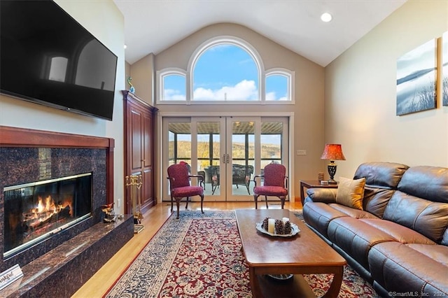 living room with french doors, a premium fireplace, light hardwood / wood-style flooring, and high vaulted ceiling