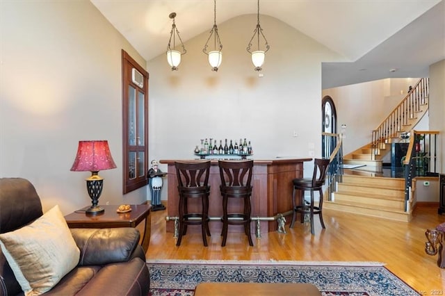 bar with pendant lighting, vaulted ceiling, and hardwood / wood-style floors