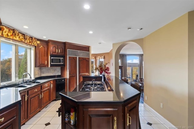 kitchen featuring plenty of natural light, stainless steel appliances, a center island, and sink