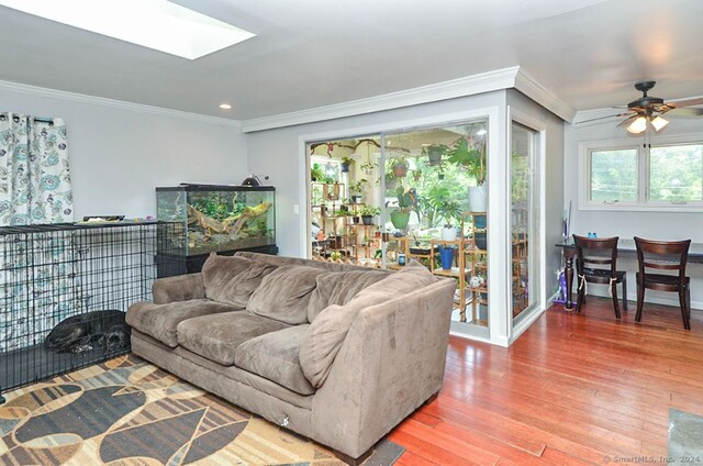 living room with ornamental molding, hardwood / wood-style flooring, a skylight, and ceiling fan