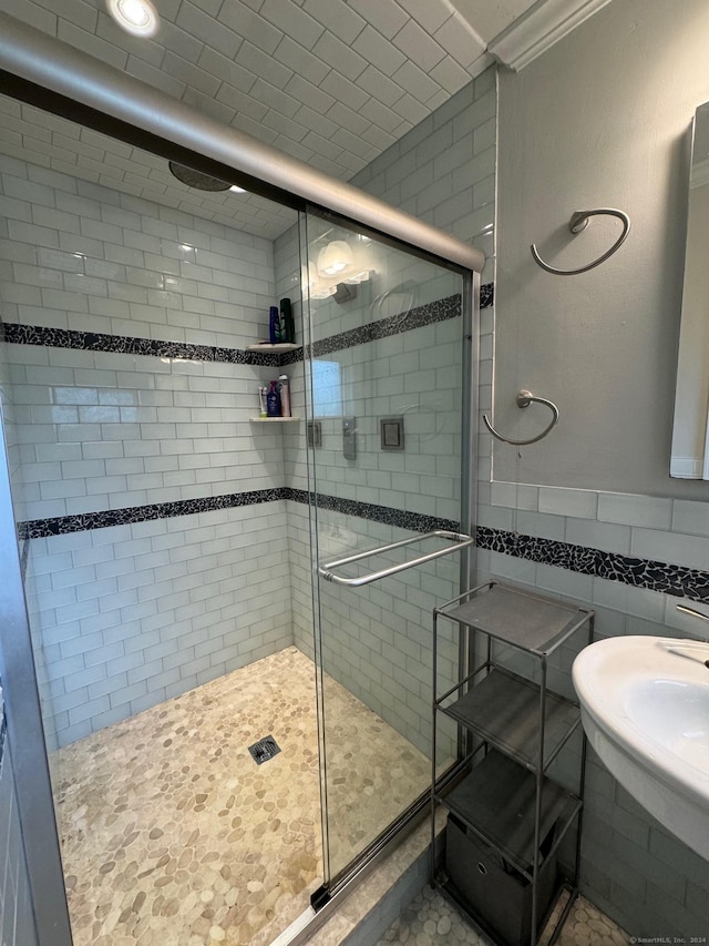 bathroom featuring an enclosed shower, sink, and tile walls