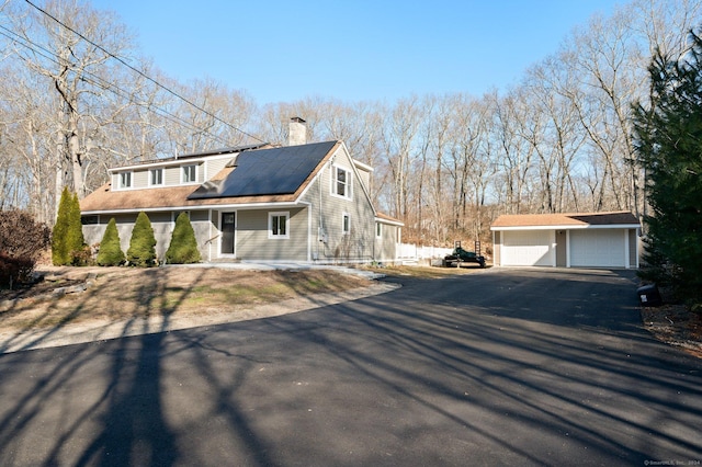 view of front of property featuring solar panels, a garage, and an outdoor structure