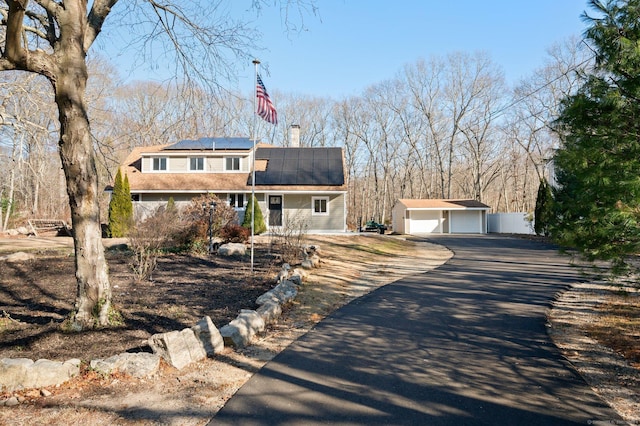 view of front of property featuring solar panels, a garage, and an outdoor structure