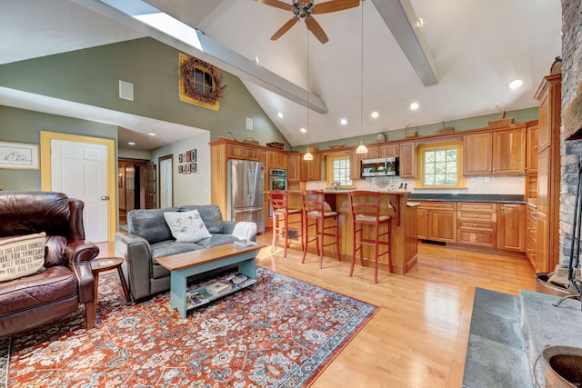 living room featuring ceiling fan, light hardwood / wood-style floors, and vaulted ceiling with beams