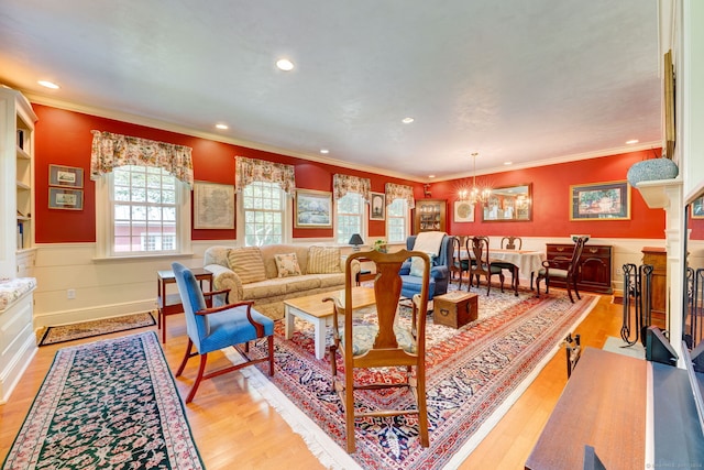 living room featuring light wood-type flooring, ornamental molding, and a notable chandelier