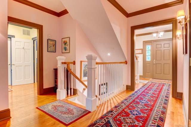 foyer entrance featuring light wood-type flooring, a chandelier, and crown molding