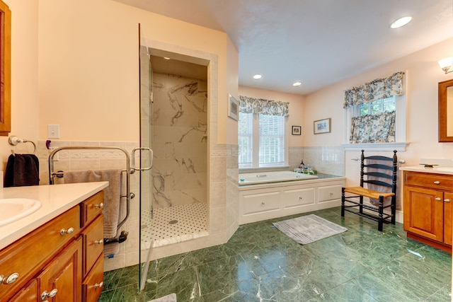 bathroom with tile walls, vanity, and shower with separate bathtub